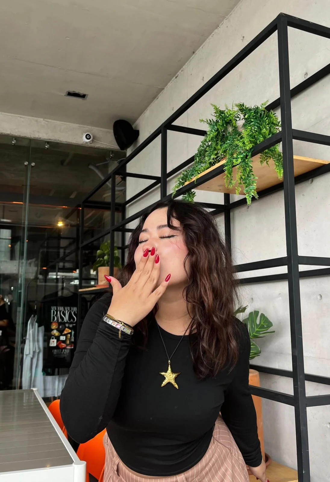 Alessa mandando un beso, con uñas rojas almendradas y un collar de estrella